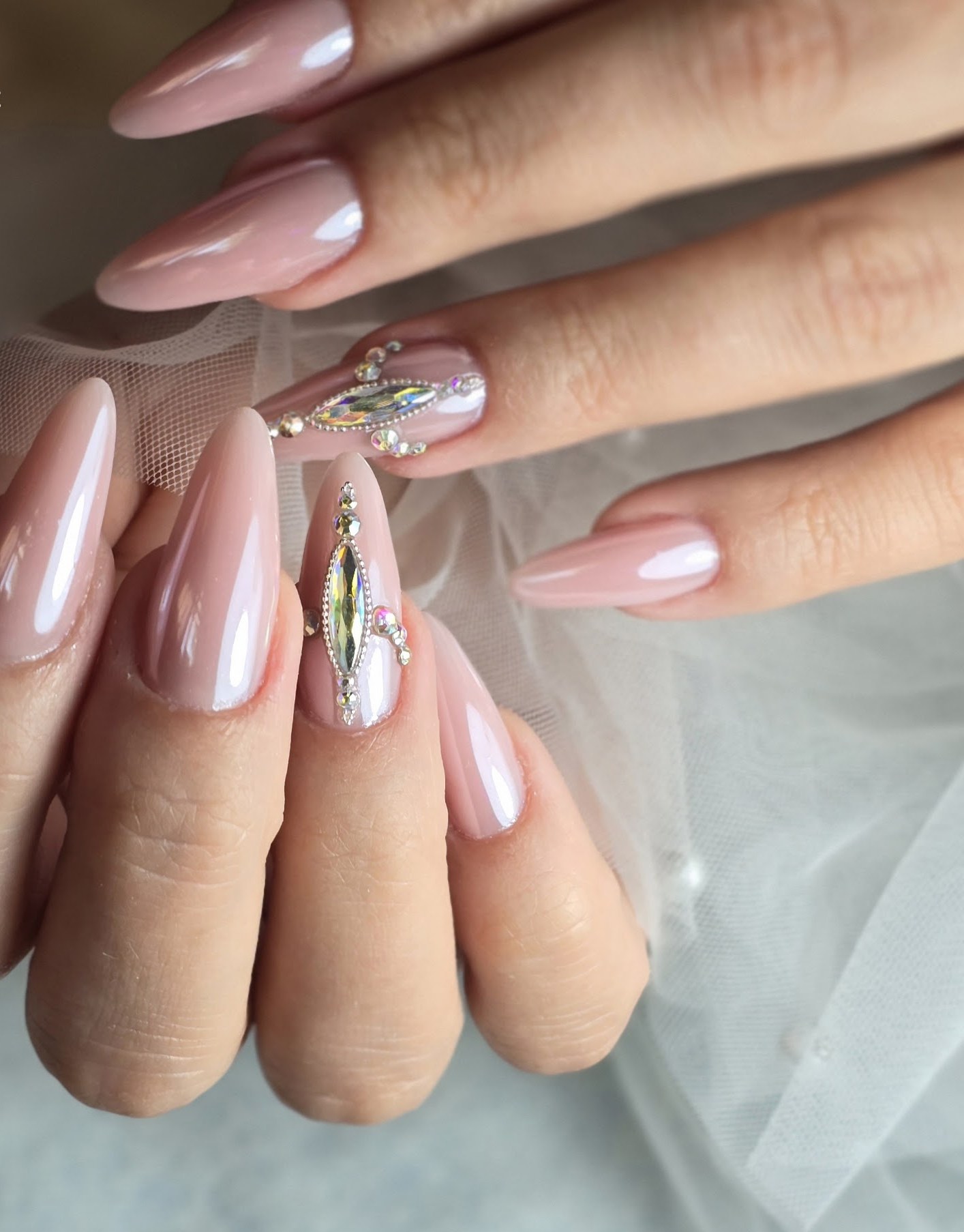 Nude chrome amandelnagels met een kristal, op tule